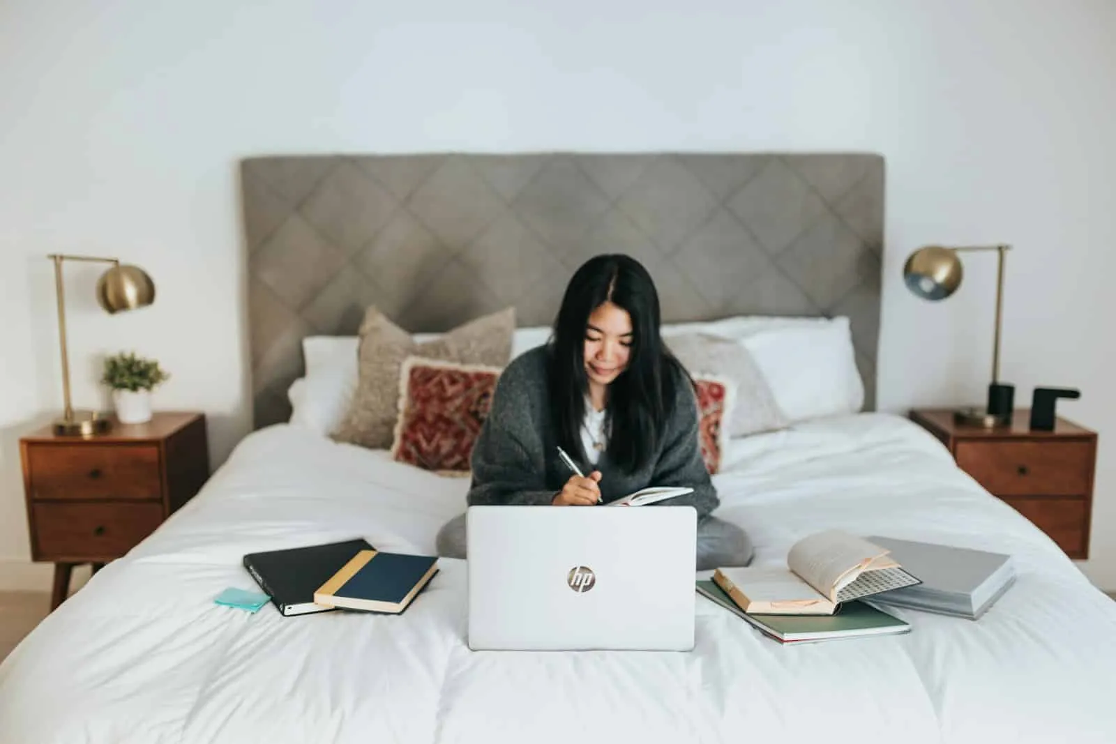 woman sitting on bed using laptop